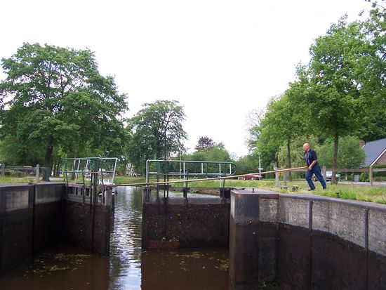 mit langen Stangen schiebt der holländische Schleusenmeister die Tore auf