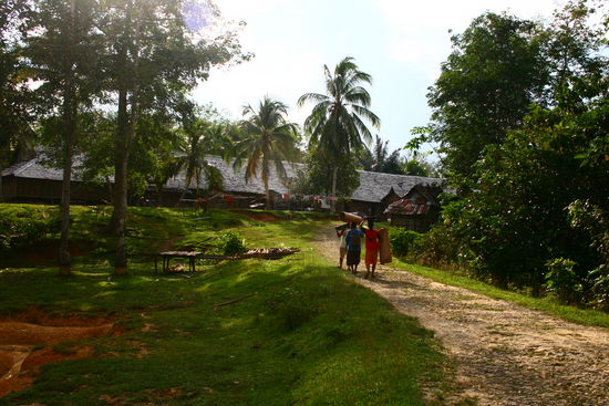 Das Longhouse im Hintergrund und die Damen, die gerade von der Arbeit kommen
