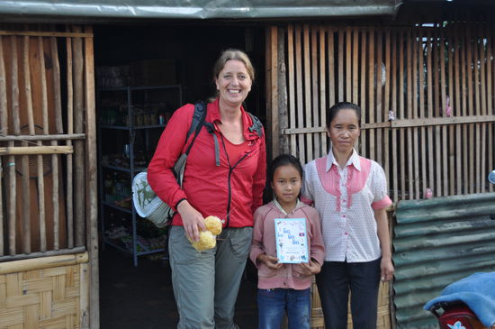 Voller Stolz zeigt die Kleine das Bilderbuch mit unterschriften in Lao-Englisch.