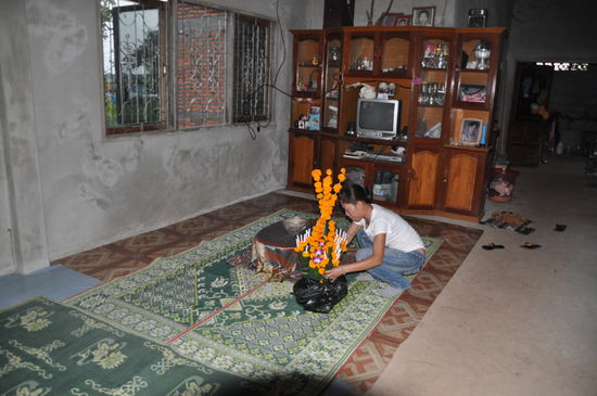 Dadang bereitet im Wohnzimmer den buddhistischen Altar für den Abend vor.