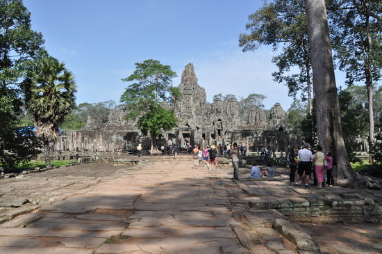 Angkor Thom die alte Tempelstadt, deren Stadtmauer im Unfang gewiss mehr als fünf Meilen lang ist. Sie hat fünf Tore. Draußen erstreckt sich ein Wassergraben, über den mächtige Dämme Zugang zur Stadt gewähren.