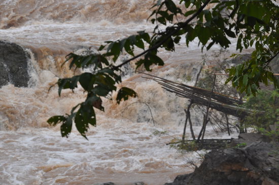 Auf dem Bambusgestänge im Vordergrund stehen oder sitzen die Fischer und ziehen in Reusen die leckeren Mekong-Fische heraus