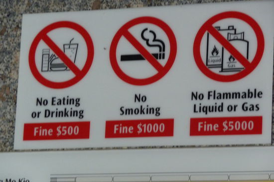 Warnschild in einer U-Bahnstation. Man brennt sich eine Kippe an und isst einen Burger - schon ist man das Jahresgehalt eines Malayen los.