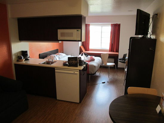 Zimmer mit Kühlschrank, Spüle, Sofa und Safe