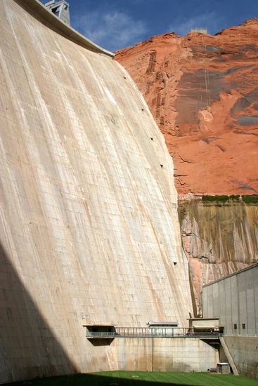 Die Stahlbetonmauer die den Colorado River zum Lake Powell aufstaute hat eine Höhe von 213 m vom Felsgrund an der Sohle bis zur Mauerkrone. Die Länge der Dammkrone beträgt 475 m.
Bauzeit von 1957 bis 1964.
Eingeweiht wurde die Anlage am 22. September 1966 von der Gattin des US-Präsidenten Johnson.