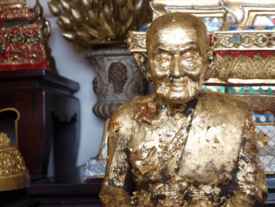 Die Glaeubigen kleben Blattgold an die Statuen.
