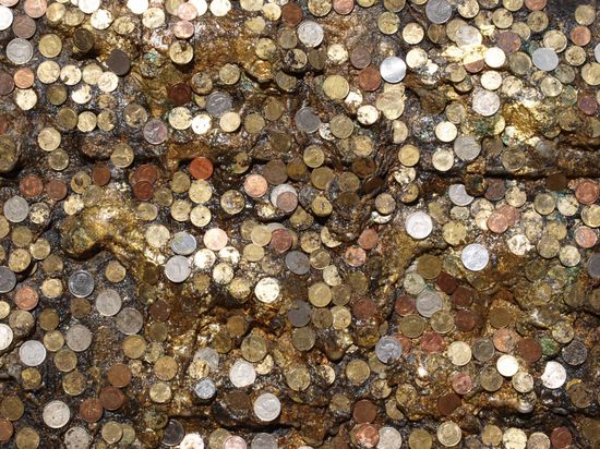 Muenzen die an den Fuss einer Buddhastatue geklebt wurden.