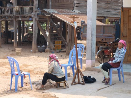 Frauen mit tragbarem Tropf vor dem Krankenhaus.