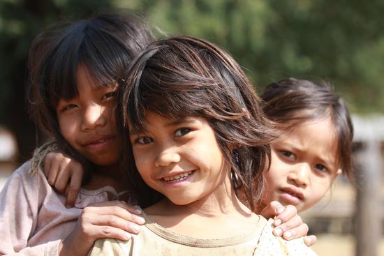 Arm aber gluecklich. Drei strahlende Kinder aus dem Dorf Ban Kiang Tangle