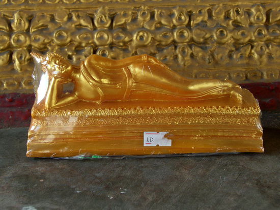Bisweilen macht er es sich auch im Liegen bequem. Dann verbraucht er mitunter im irdischen Dasein eine Menge Platz, wie zum Beispiel im Wiharn des liegenden Buddha (Wat Pho). Auf dem Bild oben waren es kaum 10 Zentimeter, banal in Folie eingeschweißt. Dabei symbolisiert gerade diese Haltung die Bedeutsamste. Glücklich und Zufrieden zieht der Erleuchtete im Augenblick seines Todes ins Nirwana ein.
