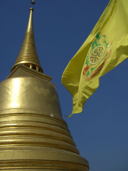 Goldener Stupa mit Königflagge auf dem Tempeldach