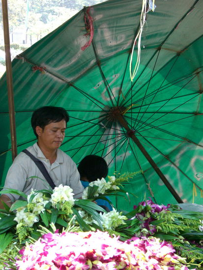 Ein Händler des Pak Khlong Market und einem schattenspendeden Sonnenschirm