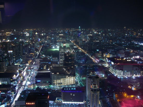 Mit Blick in südlicher Richtung ist das Parkhaus des  Paragon-Einkaufszentrum im Vordergrund. Die Grünfläche dahinter: der Royal Bangkok Sports Club.