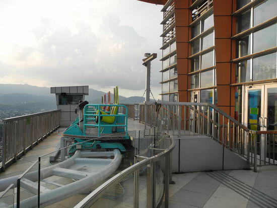 Die Wagen der Achterbahn warten auf Fahrgäste. Gerade ist augenscheinlich nicht viel los. Das liegt wahrscheinlich an dem happigen Fahrpreis und der relativ kurzen Dauer der Fahrt. Von der Achterbahn hatte ich eine andere Vorstellung. Hier gibt es keine rasante Fahrt in luftiger Höhe, mit scharfen Kurven und vielleicht einen Looping. Die Waggons bewegen sich hier eher gemächlich über den Schienenstrang. Der besondere Thrill besteht hier, dass sich die Gondeln nach vorne kippen lassen und man das Gefühl hat den Abgrund herunter zu stürzen. Den Kippwinkel können die Fahrgäste selbst bestimmen. Doch der kleine Fotograf animiert zu einer möglichst steilen Einstellung, als ob das Gekreische auf den Aufnahmen zu hören sei.