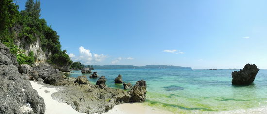 Die zunehmende Anzahl von schwarzem Felsgestein machen den Strandspaziergang zu einem Slalomparcours. Hier endet der Südabschnitt des White Beach an einer Klippe. Algen färben das Wasser grün. Hier ist es für den Badenden nicht mehr so einladend. Hier soll die Meeresströmung stärker sein. Weit und breit ist niemand von der sowieso schon spärlich ausgestatteten Strandwache zu sehen.