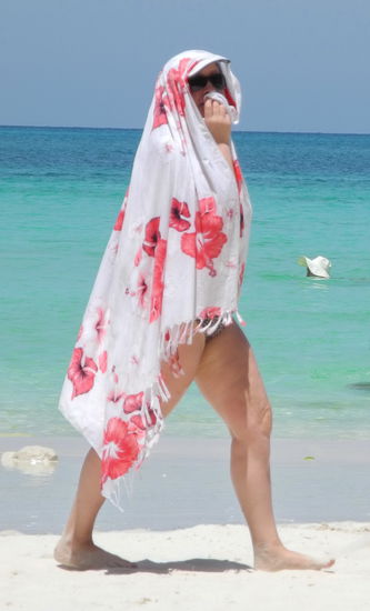 Eine Frau hat sich zum Schutz vor der Sonne fast gänzlich mit ihrem Badelaken vermummt.