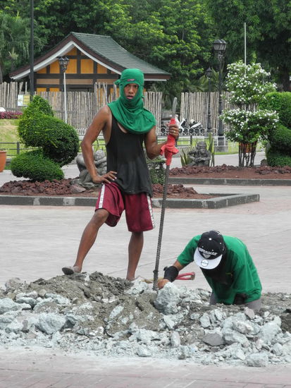 An einigen Teilen des Parks werden die Gehwege instand gesetzt. Die Arbeiter schützen sich mit um den Kopf gebundenen Pullovern vor der Sonne