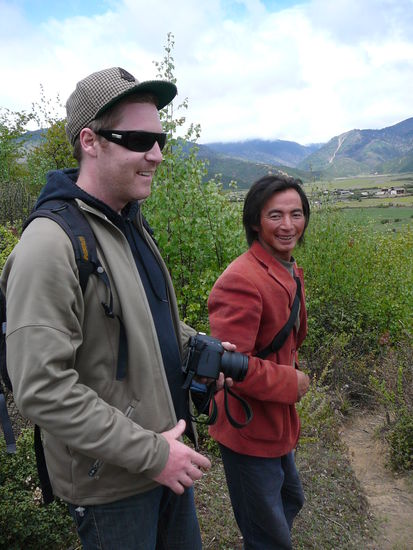 Kevin und Kesang, der Gastvater, waehrend er  uns sein Land mit den Tieren und Feldern zeigt.