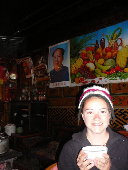 Links ueber mir: Chairman Mao (erstaunlicherweise, in einem tibetischen Zuhause), Fruechteposter , auf mir: ein klassischer Hut fuer die tibetische Frau (den hatte mir die Grossmutter aufgesetzt und immer gesagt, wie schoen das aussieht), in meinen Haenden der phaenomenal eklige tibetische Yak-Butter-Tee, den wir immer nachgefuellt bekamen... Es war toll!!!