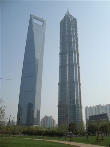 Links das Shanghai World Financial Center (492m), rechts das Jin-Mao-Gebaeude (420m). Man beachte die Fensterputzer unterhalb des Rhombus des World Financial Centers. Die 15-stoeckigen Hochhaeuser daneben sehen aus wie Lego-Haeuschen...