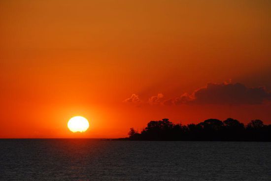 Sonnenuntergang am Rio de la Plata. Nur bei sehr guter Sicht kann man die Skyline der etwa 40 km entfernten Metropole Buenos Aires erkennen.