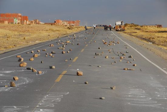 Ueber etliche Kilometer ist die Strasse voller Steine, sodass Fahrzeuge nicht mehr durch kommen. Im Hintergrund ist eine von mehreren Blockaden der Minenarbeiter zu erkennnen.