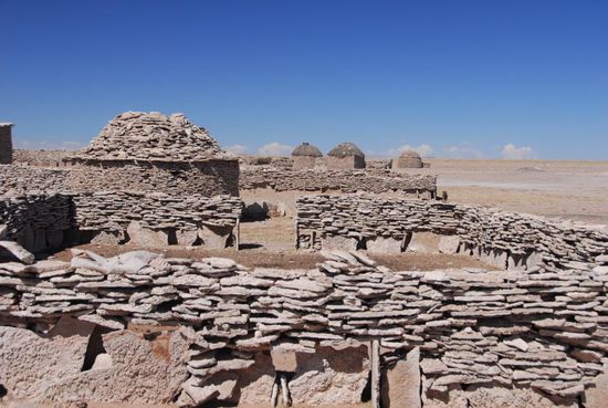 Als Baumaterial dient, was die Landschaft hergibt. Hier sind es flache Steinplatten, mit den die Haeuser der Chipaya zum Teil aufgeschichtet werden. Am Rande des Salar do Coipasa praegen die Rundhuetten dieses uralten Volksstammes das Landschaftsbild