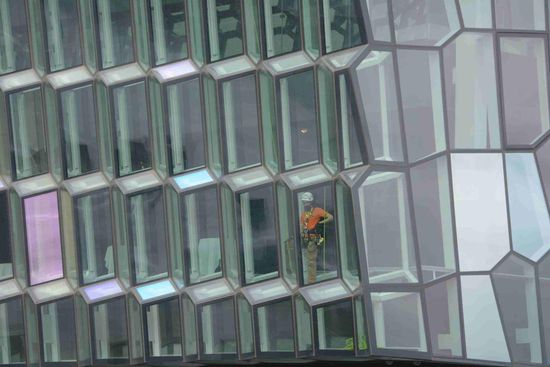 Fensterputzer mit Kletterausrüstung im Innern der Glasfassade