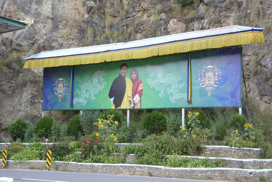 Thimphu kündigt sich mit einem aufwändigen Tor an und vom Plakat lächelt einem das allgegenwärtige Königspaar entgegen