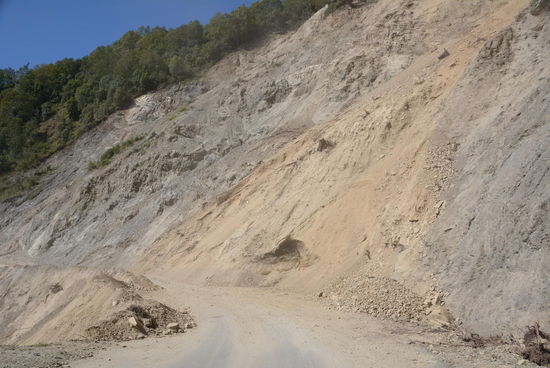 Zur Straßenverbreiterung wird der Hang abgetragen, dadurch wird dieser instabil, rutscht auf die neue Fahrbahn und verschüttet oder zerstört sie wieder. Dutzende Erdrusche lassen keine Ende der Arbeiten absehen. Oft wird wie Fahrbahn nur für eine Fahrzeugbreite wieder frei geräumt.