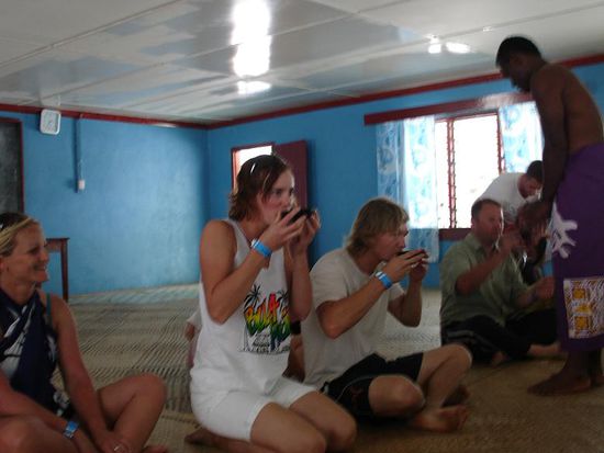 - Beim Kava-Probieren -
Es schmeck nicht besonders genuesslich, aber man darf nicht das Gesicht versziehen...
"Kava" ist eine Art Droge, da die Fijianer keinen Alkohol trinken duerfen. Das Pulver wird aus den Wurzeln eines Baumes hergestellt und mit kaltem Wasser vermischt und getrunken. 
Schmeck nach Holz, Nuss und ein bisschen Kakao. 
Es wirkt beruhigend, entspannend....und die Zunge und der Mund werden ganz taub.