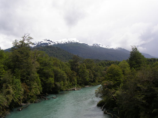 Kleiner Fluß, Urwald und schneebedeckte Berge.