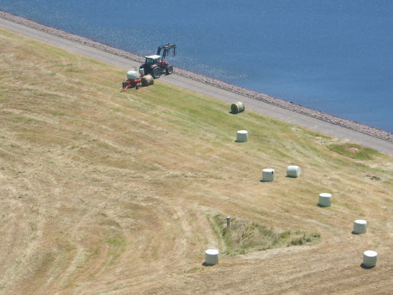 Traktor beim Heupressen und einwickeln.