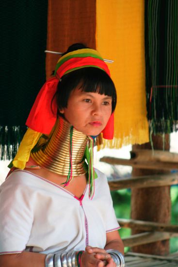 Das PADONG-KAREN Dorf - hier leben die Langhalsfrauen
Vor ungefähr einhundert Jahren sind die ersten Angehörigen des Karen-Volkes von Myanmar (Burma) nach Thailand eingewandert. Auch heute noch gibt es Gruppen von Karen, die versuchen, die thailändisch-burmesische Grenze zu überschreiten, um sich in Thailand niederzulassen. Die thailändischen Behörden versuchen allerdings mit allen Mitteln, die neu zugewanderten Karen davon abzuhalten, sich auf thailändischem Boden einzuquartieren.
Es gibt unterschiedliche KAREN Dörfer, diese Gruppe heisst Padong-Karen und ist weithin bekannt wegen ihren Frauen mit den langen Hälsen. 
Man ist hier der Ansicht, dass lange Hälse schwanenartig seien und daher ein Zeichen der Schönheit sind. 
In dem Museum beim Goldenen Dreieck haben wir einiges über die verschiedenen Dörfer gelesen und da stand, dass der Ursprung der Ringe auf die Zeit zurückführt, als es noch Tiger gab. Und durch die Ringe versuchten die Männer die Frauen und Mädchen zu schützen, da der erste Biss des Tigers immer am Hals ist!
Und da stand auch, dass der längste Halsring, der jemals gesehen wurde 25 mal um den Hals geht. Wahnsinn finde ich!