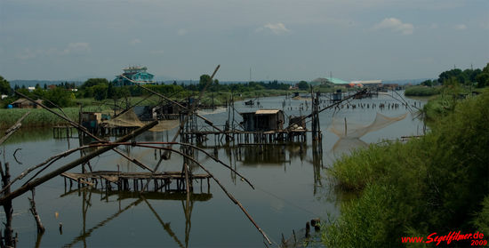 Pfahlbauten auf dem Flüsschen Brdela, auf denen Fischer an langen Stangen ihre Netze aufhängen. Vorwiegend wird hier Aal gefangen.
