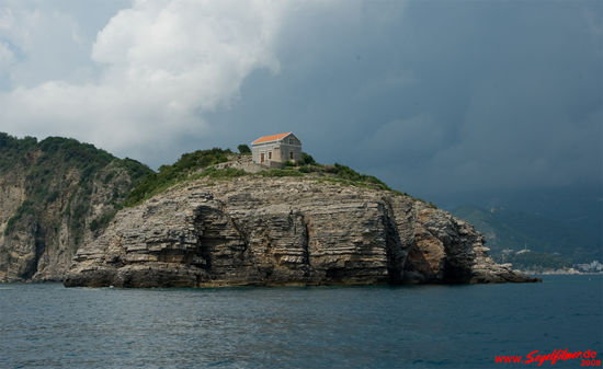 Der Leuchtturm auf der der Bucht vorgelagerten kleinen Insel Sveti Nikola bei Budva vom Meer ausgesehen