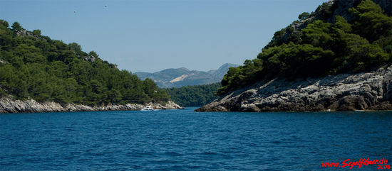 Blick von der Meerseite in die schmale Durchfahrt zwischen den beiden Inseln Jakljan und Sipan. Im Hintergrund sind die Berge auf dem Festland zu sehen.