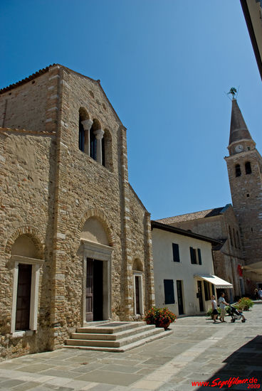 Der streng rechteckige Bau der Taufkirche (6. Jh.) erhebt sich nördlich des Domes, der am rechten Bildrand ebenfalls noch sichtbar ist.