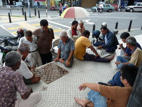 Ich glaube das ist Dame was die hier spielen. Als Spielsteine wurden Bierdeckel verwendet 