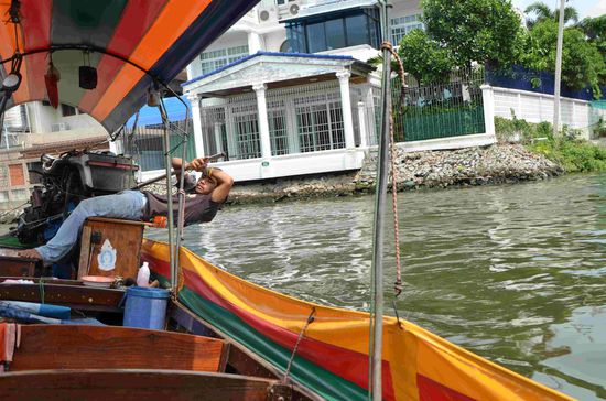 So ein Longtailboot ist etwa 8m (?) lang und könnte ungefähr 15 Menschen Platz bieten. Das Steuern in den engen Kanälen kann durchaus schwere Arbeit bedeuten.