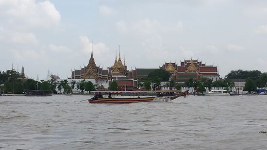 Ein typisches Boot fährt vor dem großen Palast vorbei.