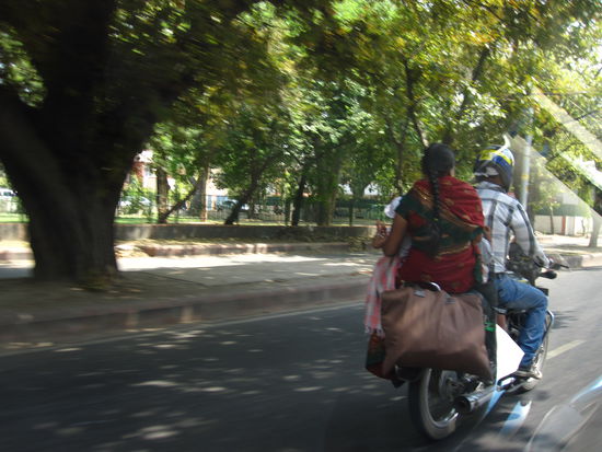 Genau hinsehen: die Dame nicht nur ohne Helm, sondern freihaendig, da 2 Kinder unterm Arm