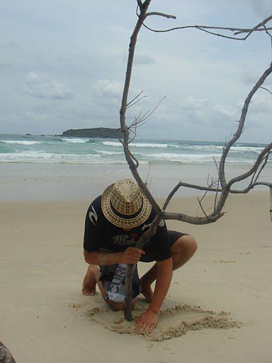 Martin pflanzt einen Baum am Strand.