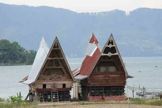 Batakhaeuser. Es gibt drei Etagen, wie die drei Stufen ihres Glaubens. Unten das Boese, in der Mitte wohnt die Familie, oben ist das Gute. Dies sind einfache Haeuser. Oft sind die Haeuser auch noch extrem verziert, durch Holzschnitzereien.