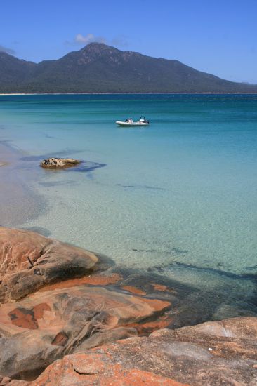 Tuerkisblaues Meer, feuerrote Steine und schneeweisser Sand