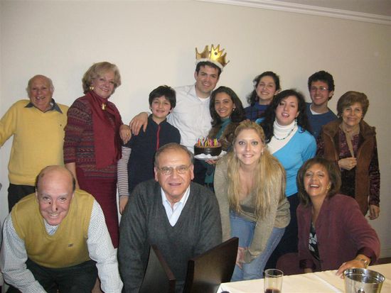 Ganz links die beiden, die stehen, sind meine Gasteltern. Der mit der Krone Stanley und die Frau mit dem Kuchen seine Frau Muriel. Die Frau mit dem weißen Rolli ist die andere Tochter und meinen Gasteltern. Sie hat 3 Kinder. die blonde Frau ist Muriels Schwester und die beiden links und rechts von ihr sind ihre Eltern. Die ältere Frau ganz rechts ist die schwester von meiner Gastmutter.