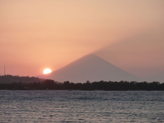 Der Sonnenuntergang mit Blick nach Bali. Die Sonne versinkt hinter dem Vulkan auf Bali.