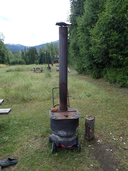 Der Ofenuntersatz aus Rasenmäherfüßen, einer Waschtrommel für das Holz und ein langes Ofenrohr- genial
