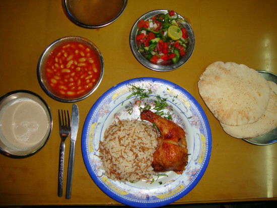 aegyptischen Essen aus der Garkueche: Huehnchen, Reis, Salat, Bohnen in Tomatensosen, Tomatengurkensalat mit Kraeuter, Pita Bort und Tehina (Auberginenmuss)