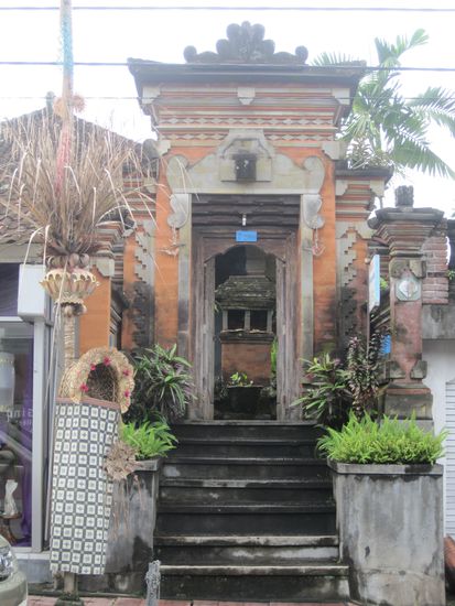 Eingang zu einem privaten Anwesen mit dahinterliegendem Tempel, davor ein Penjor 